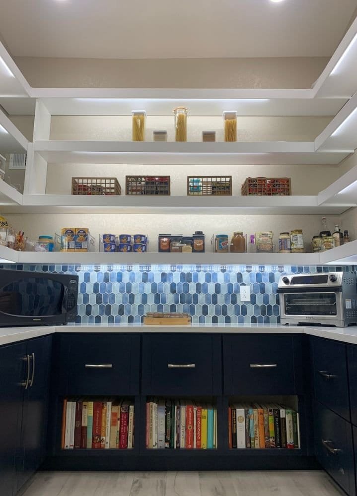 A kitchen with blue cabinets and bookshelves, organized by a professional organizer.