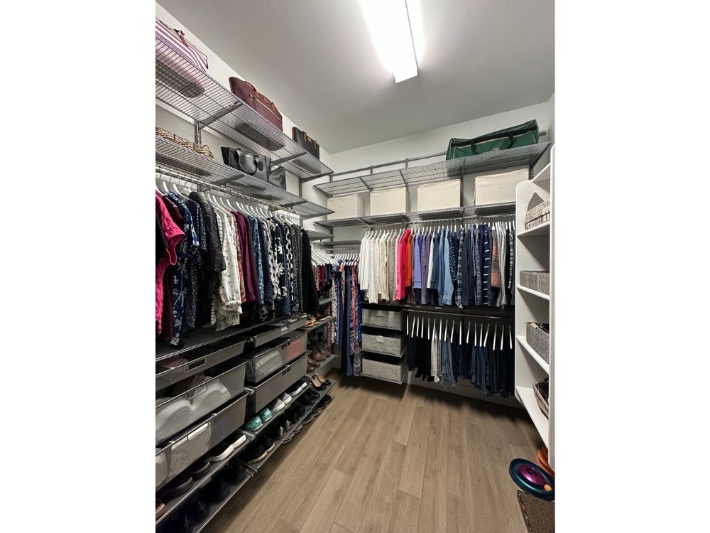 A Melinda's custom designed walk-in closet with clothes hanging on racks.