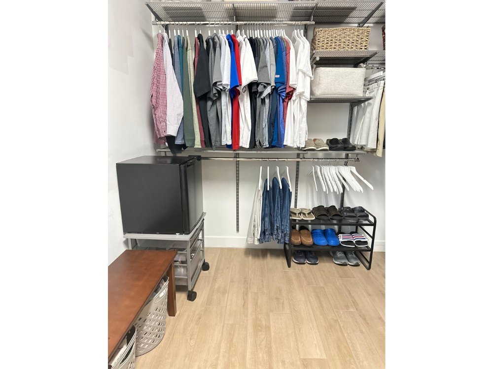 Melinda's custom designed closet boasts an impressive collection of clothes and shoes, while also featuring a convenient refrigerator for refreshments.