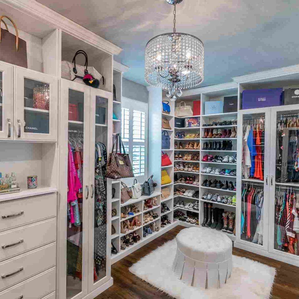 A professionally organized walk-in closet with a chandelier and an abundance of shoes.