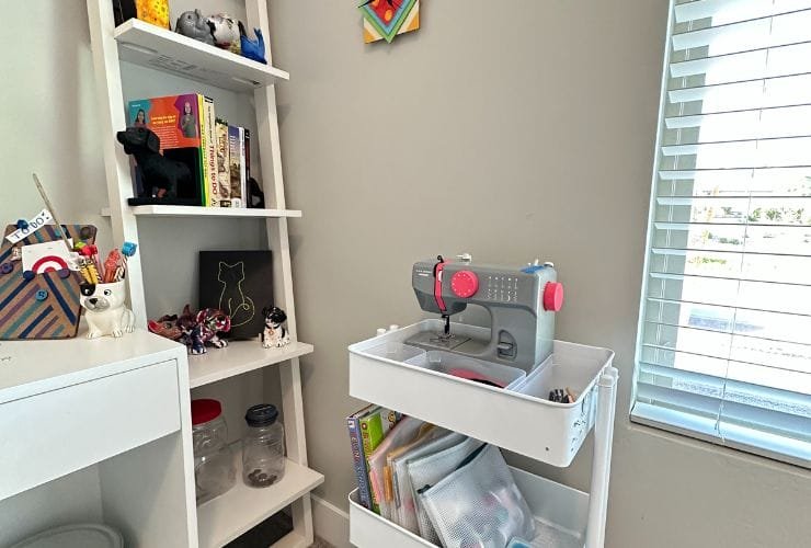 A white shelf with a sewing machine and other supplies, organized by a professional organizer in closets.