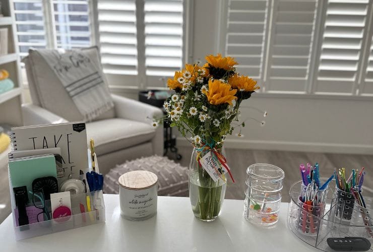 A professional organizer's desk with a vase of flowers and pens.