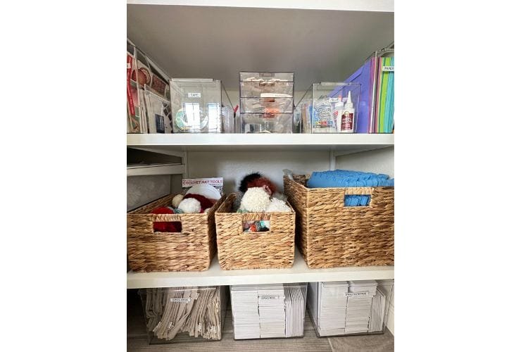 Professional organizer arranging wicker storage baskets in a closet.