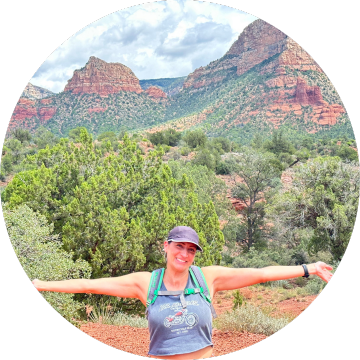 A woman with her arms outstretched in front of a majestic red rock mountain, feeling at home in nature's embrace.